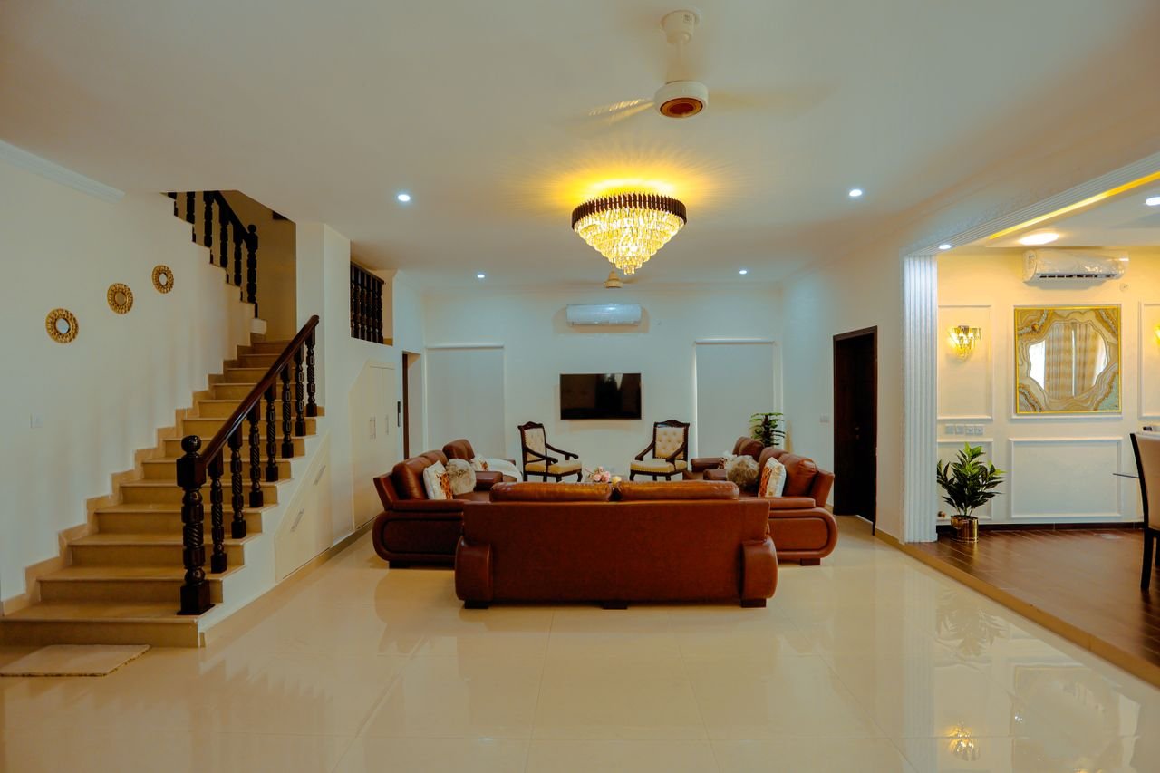 Home Spacious modern living room with leather sofas and elegant chandelier, ideal for real estate.