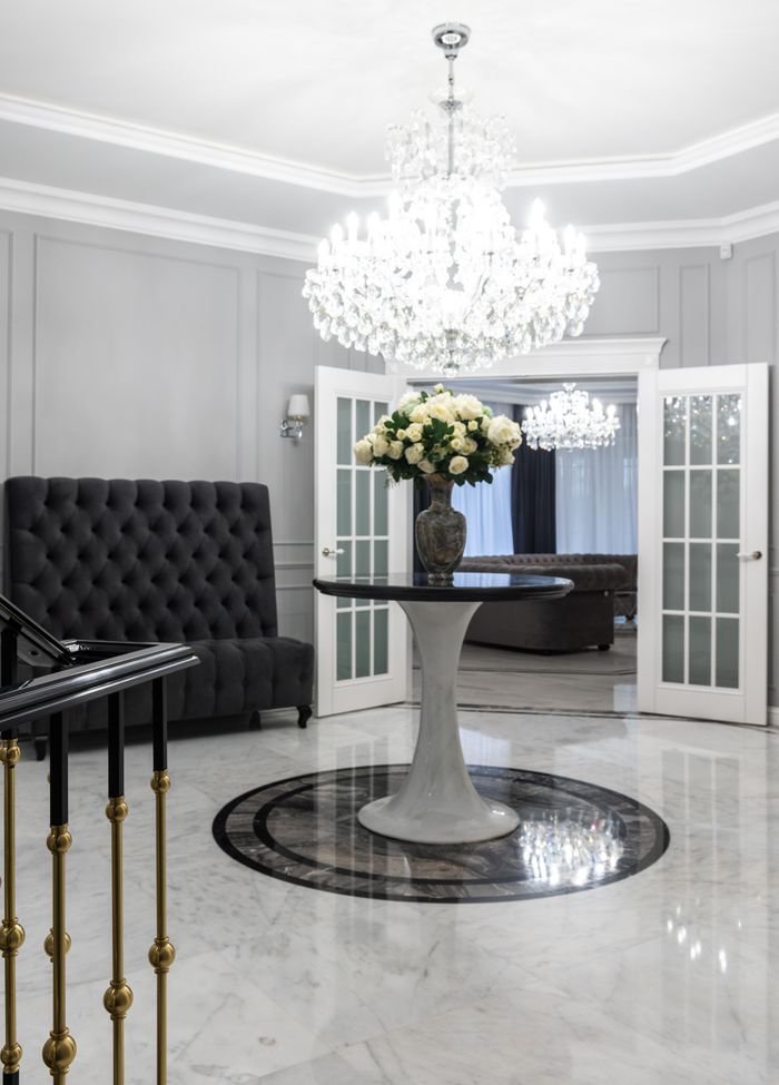 Mastering the First Impression: Your intriguing post title goes here Elegant bouquet of fresh white roses in vase placed on round table in hallway of luxury villa with comfy armchair and crystal chandeliers