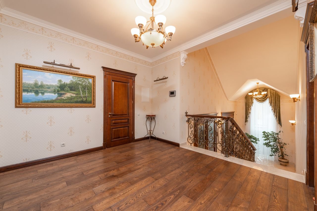 Home Spacious home interior showcasing elegant staircase, chandelier, and wooden floor.